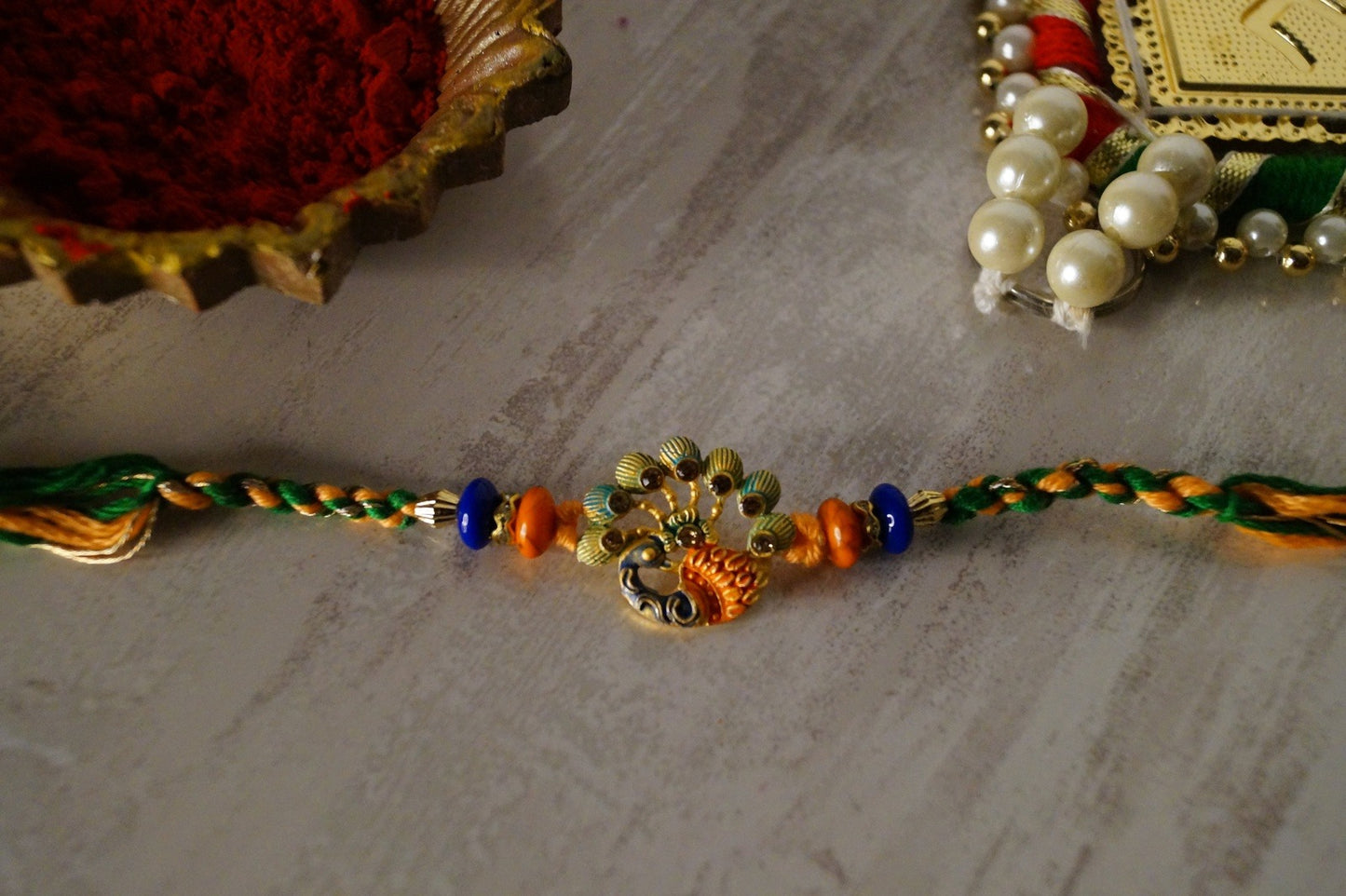 Peacock Stone and Gold Brass Thread Rakhi at Kamakhyaa by Kamakhyaa. This item is jewelry, Multicolor, Natural, Rakhi, Under 1500, Under 1750, Upcycled